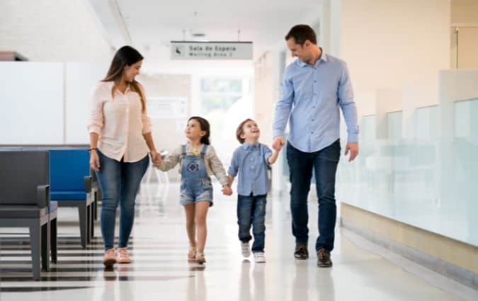 Család kézenfogva sétál egy magánegészségügyi intézményben