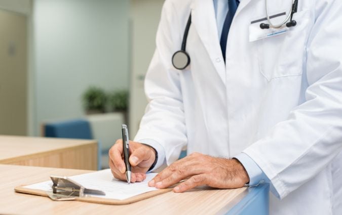 Orvos papírokat olvas egy rendelőben