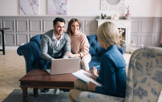 Család pénzügyi tanácsadóval, aki a kockázati életbiztosítás költségeit magyarázza